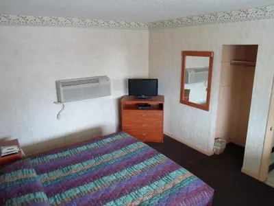 a bedroom with a bed and a tv and a mirror at Red Carpet Inn Brooklawn in Brooklawn