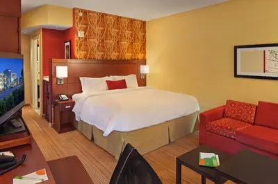 a hotel room with a large bed and a red couch at Courtyard Philadelphia Coatesville Exton in Coatesville