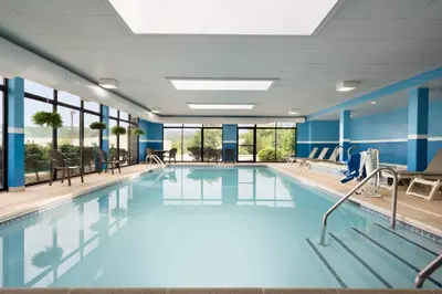 a large swimming pool with blue walls and windows at Holiday Inn Express & Suites - North Brunswick by IHG in North Brunswick