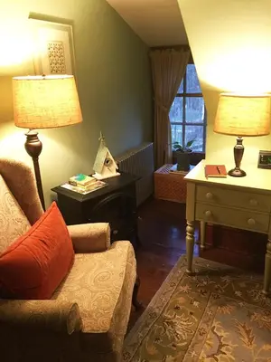 a living room with a chair and a desk and a lamp at The Lancaster Bed and Breakfast in Lancaster