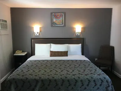 a bedroom with a bed with two lights on the wall at Scottish Inns Milford in Milford