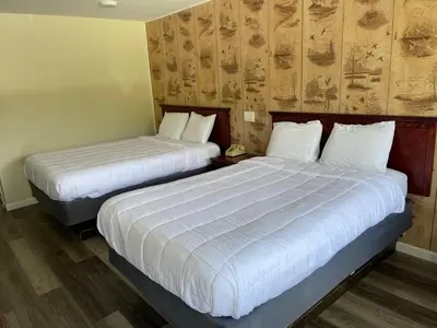 two beds in a hotel room with white sheets at Paramount Motel Pocono in East Stroudsburg