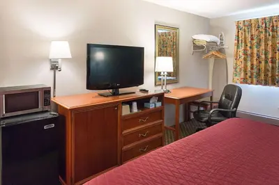 a hotel room with a bed and a flat screen tv at Rodeway Inn Milford - I-84 in Milford