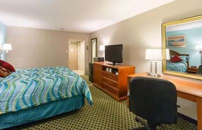 a hotel room with a bed and a desk and a television at Rodeway Inn Milford - I-84 in Milford