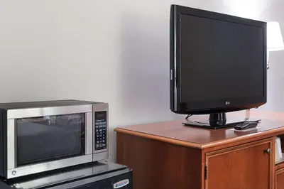 a television and a microwave on a wooden cabinet at Rodeway Inn Milford - I-84 in Milford