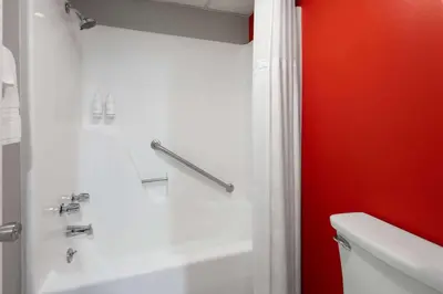 a bathroom with a shower with a red wall at Super 8 by Wyndham Hazleton in Hazleton