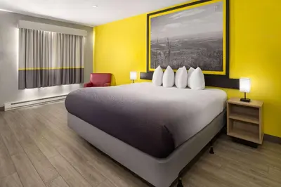 a hotel room with a large bed and yellow walls at Super 8 by Wyndham Hazleton in Hazleton