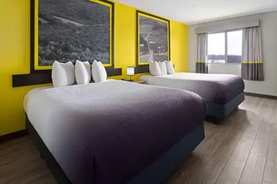 two beds in a hotel room with yellow walls at Super 8 by Wyndham Hazleton in Hazleton