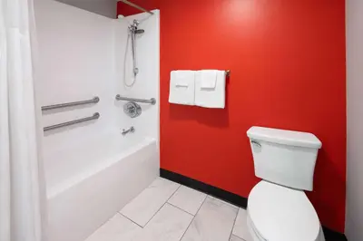 a bathroom with a white toilet and a red wall at Super 8 by Wyndham Hazleton in Hazleton
