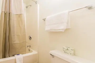 a bathroom with a toilet and a shower with towels at Travelodge by Wyndham Essington / Philadelphia Airport in Essington