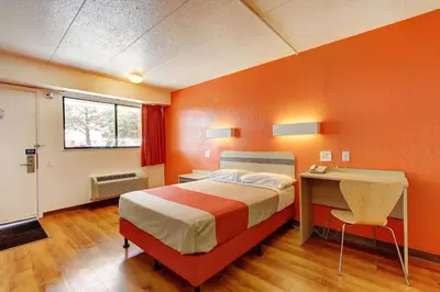 a orange bedroom with a bed and a desk at Motel 6-York, PA in York
