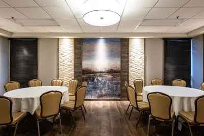 a room with two tables and chairs in front of a painting at Holiday Inn Newark International Airport in Newark