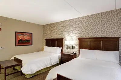 a hotel room with two beds and a table at Hampton Inn Tunkhannock in Tunkhannock