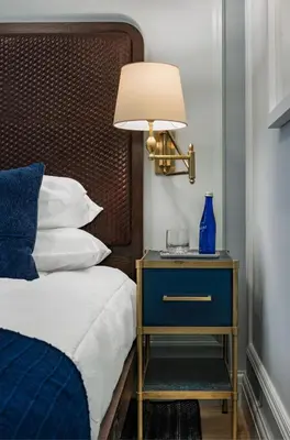 a bed with a blue night stand with a blue lamp at Merrion Row Hotel and Public House in New York