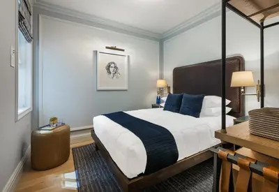 a bedroom with a king sized bed with blue pillows at Merrion Row Hotel and Public House in New York