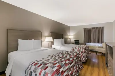 a hotel room with two beds and a desk at Red Roof Inn Denver in Denver