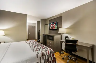 a hotel room with a bed and a desk and a tv at Red Roof Inn Denver in Denver