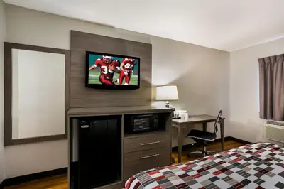 a hotel room with a bed and a tv on the wall at Red Roof Inn Denver in Denver