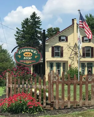 a wooden fence in front of a house with a sign at Carriage Stop Bed & Breakfast in Palmyra
