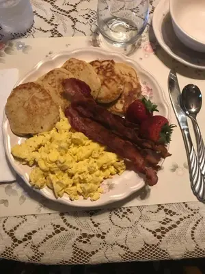 a plate of breakfast food with bacon eggs and toast at Carriage Stop Bed & Breakfast in Palmyra
