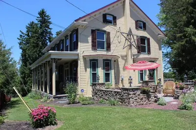 an old house with an umbrella in the yard at Carriage Stop Bed & Breakfast in Palmyra