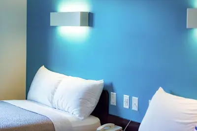 a bed with white pillows and a blue wall at Motel 6-Pottstown, PA in Pottstown