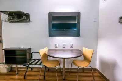 a table with chairs and a tv on a wall at Motel 6-Pottstown, PA in Pottstown