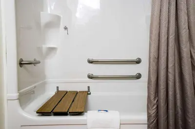 a bathroom with a bath tub with a wooden seat at Motel 6-Pottstown, PA in Pottstown