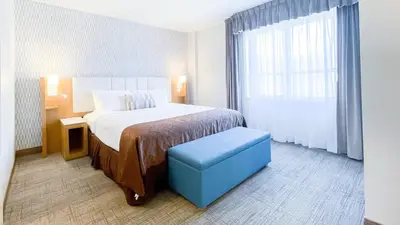 a hotel room with a bed and a blue stool at Split Rock Resort in Lake Harmony