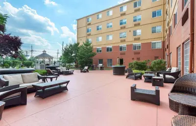 a patio with chairs and tables and a building at Extended Stay America Suites - Secaucus - New York City Area in Secaucus