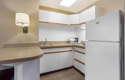 a small kitchen with white cabinets and a refrigerator at Extended Stay America Suites - Meadowlands - East Rutherford in East Rutherford