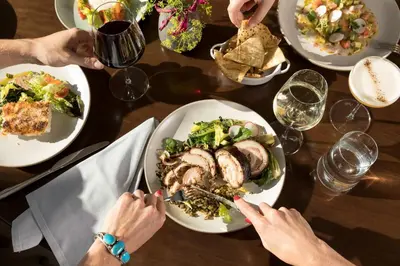a group of people sitting at a table with plates of food at The MC, Autograph Collection in Montclair