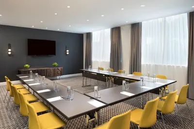 a conference room with a long table and yellow chairs at The MC, Autograph Collection in Montclair