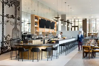 a restaurant with a bar with people in the background at The MC, Autograph Collection in Montclair
