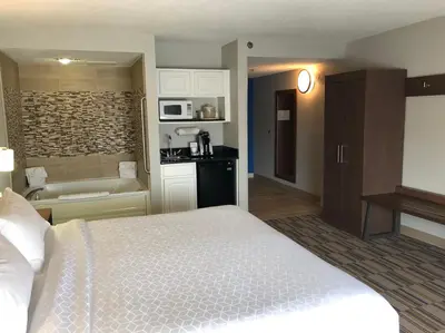 a bedroom with a bed and a bathroom with a tub at Holiday Inn Express and Suites Quakertown - Allentown Area by IHG in Quakertown