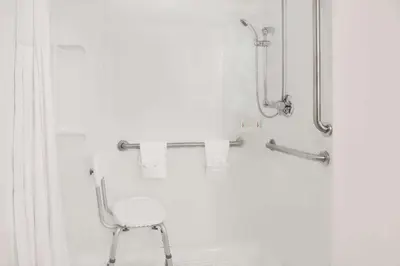 a white shower with a chair in a bathroom at Super 8 by Wyndham Danville in Danville