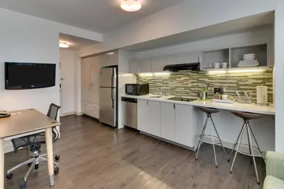 a kitchen with white cabinets and a counter with a table at Element Ewing Princeton in Ewing