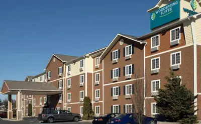 a large brick building with cars parked in a parking lot at WoodSpring Suites Allentown Bethlehem in Bethlehem