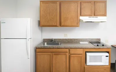 a kitchen with wooden cabinets and a white refrigerator at WoodSpring Suites Allentown Bethlehem in Bethlehem