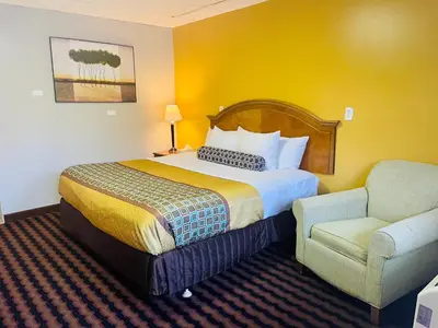 a hotel room with a bed and a chair at Red Carpet Inn Duncannon in New Buffalo