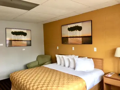 a hotel room with a bed and a chair at Red Carpet Inn Duncannon in New Buffalo