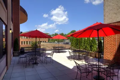 a patio with tables and chairs with red umbrellas at The Hotel Warner in West Chester