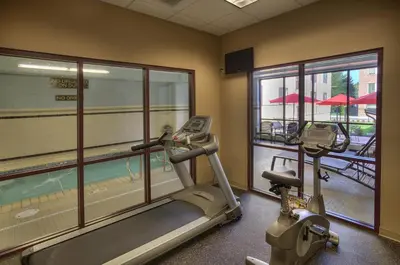 a gym with a treadmill and a view of a pool at The Hotel Warner in West Chester