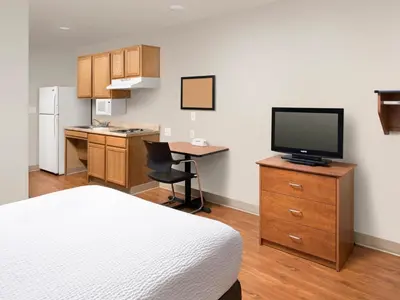 a hotel room with a bed and a desk with a television at WoodSpring Suites Wilkes-Barre in Wilkes-Barre