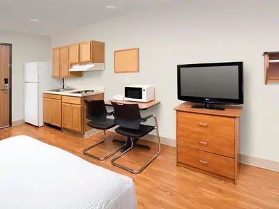 a hotel room with a television and a table and chairs at WoodSpring Suites Wilkes-Barre in Wilkes-Barre