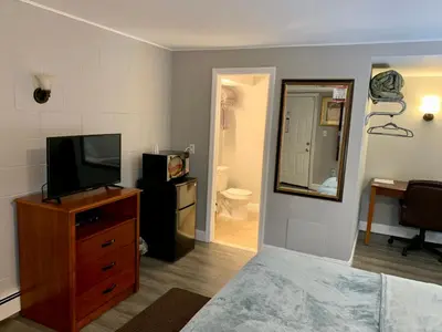 a bedroom with a television and a dresser with a mirror at Hill Top Motel in Wrightstown
