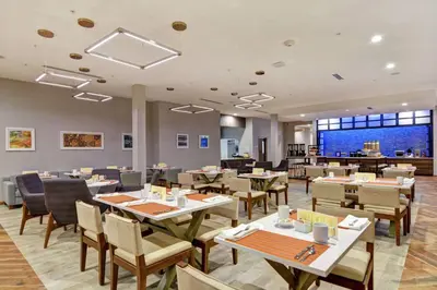 a restaurant with tables and chairs and a cafeteria at Hilton Garden Inn Princeton Lawrenceville in Lawrenceville