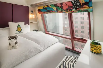 a bedroom with a white bed with a stuffed animal on it at Staypineapple, An Artful Hotel, Midtown New York in New York