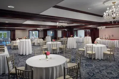 a banquet room with white tables and chairs and chandeliers at The Madison Hotel in Morristown