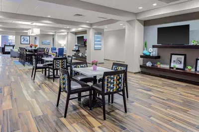 a restaurant with tables and chairs and a flat screen tv at Hampton Inn Cranbury in Cranbury